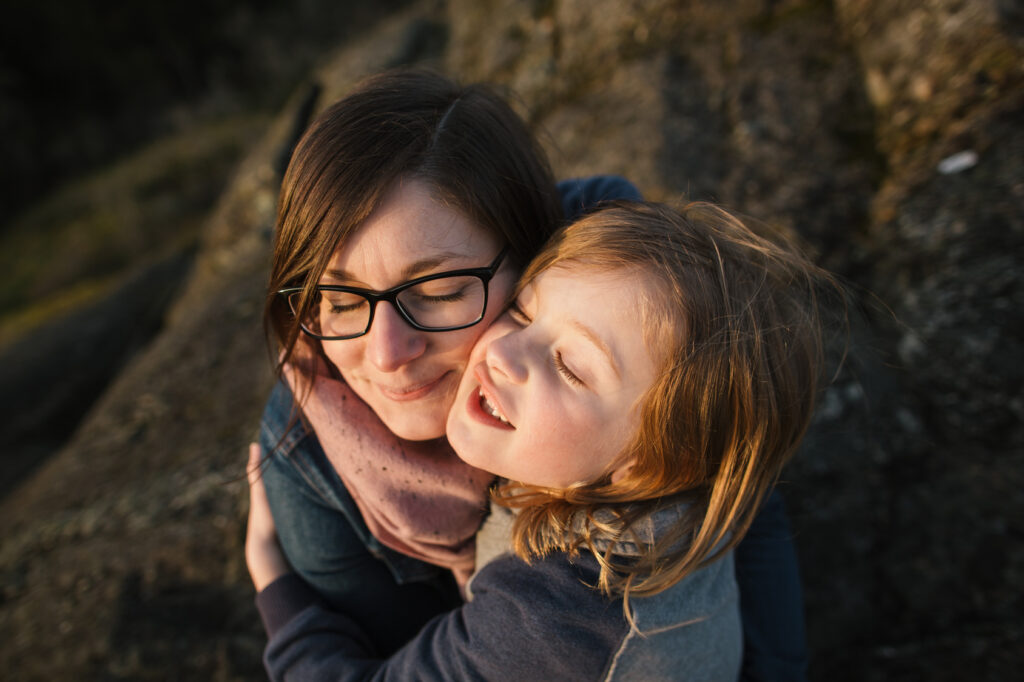 Mom with glasses hugging child. 