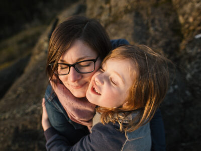 Mom with glasses hugging child.