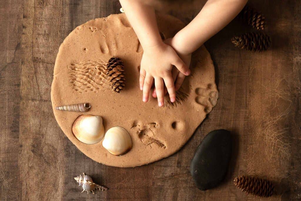 child playing with natural dough and sea shells. 