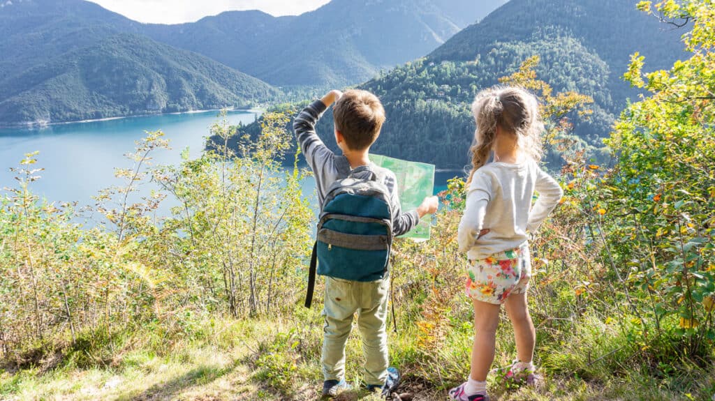 Boy and girl looking at a map and a view while on a nature walk. Fostering a love of nature in your kids. 