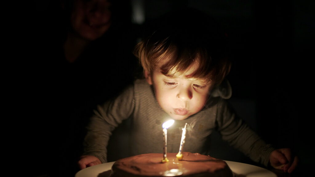  Two year old child blows candle