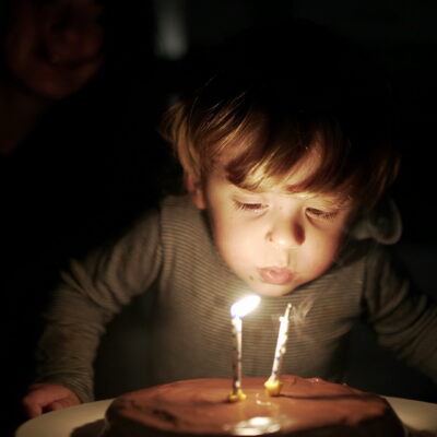 Two year old child blows candle